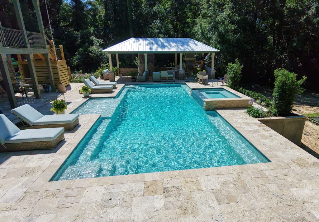 Aerial view of a rectangular pool, pale patio, and covered pavilion